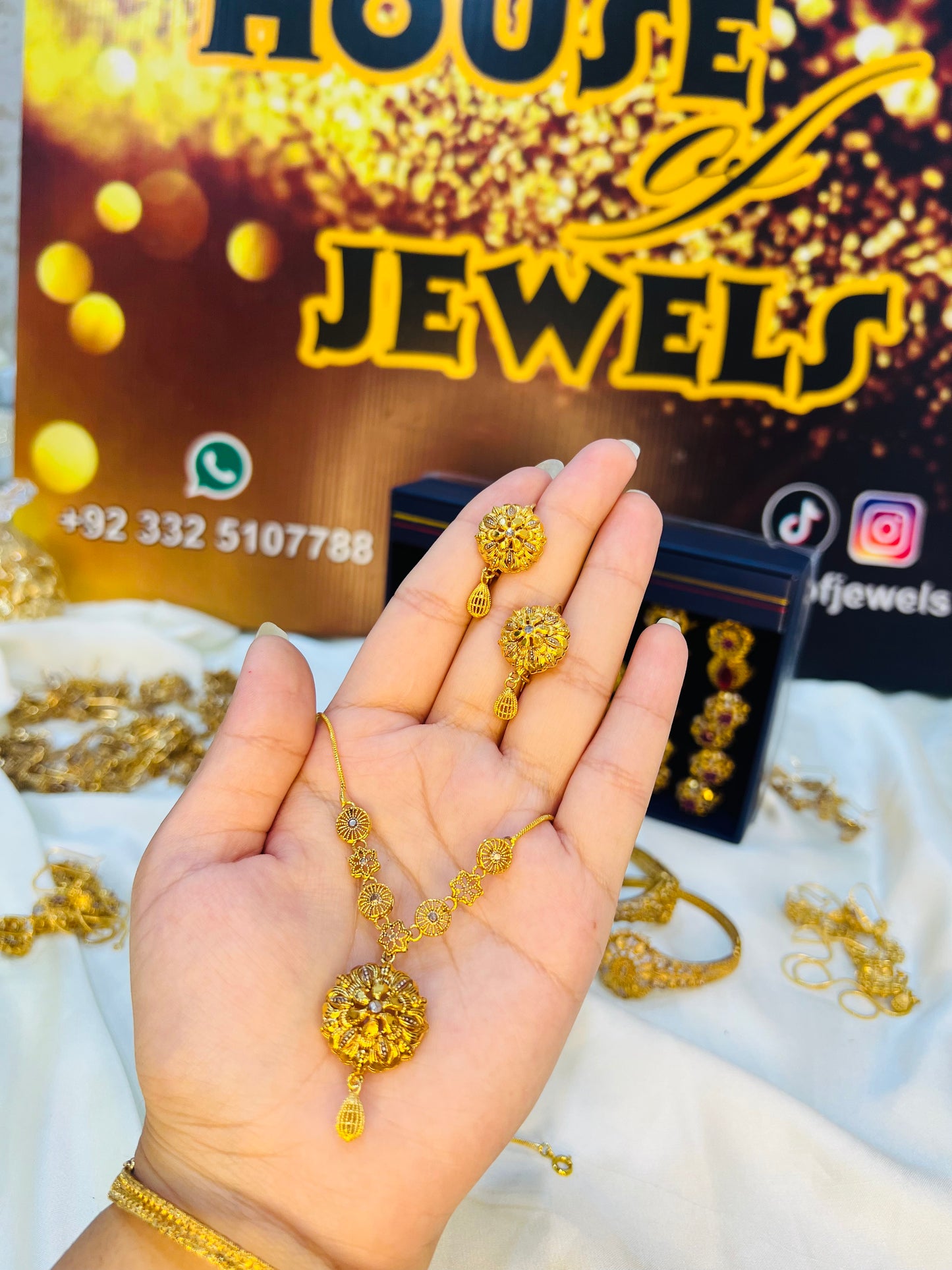 Gold jewelry set on a hand with 'House of Jewels' branding in the background